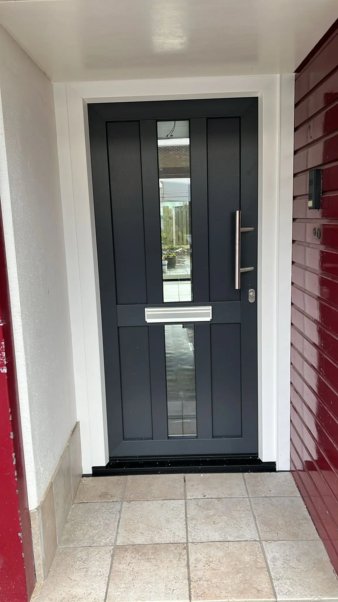 Antraciet kunststof voordeur met glasstrook in een wit kozijn bij een woning in Hengelo.