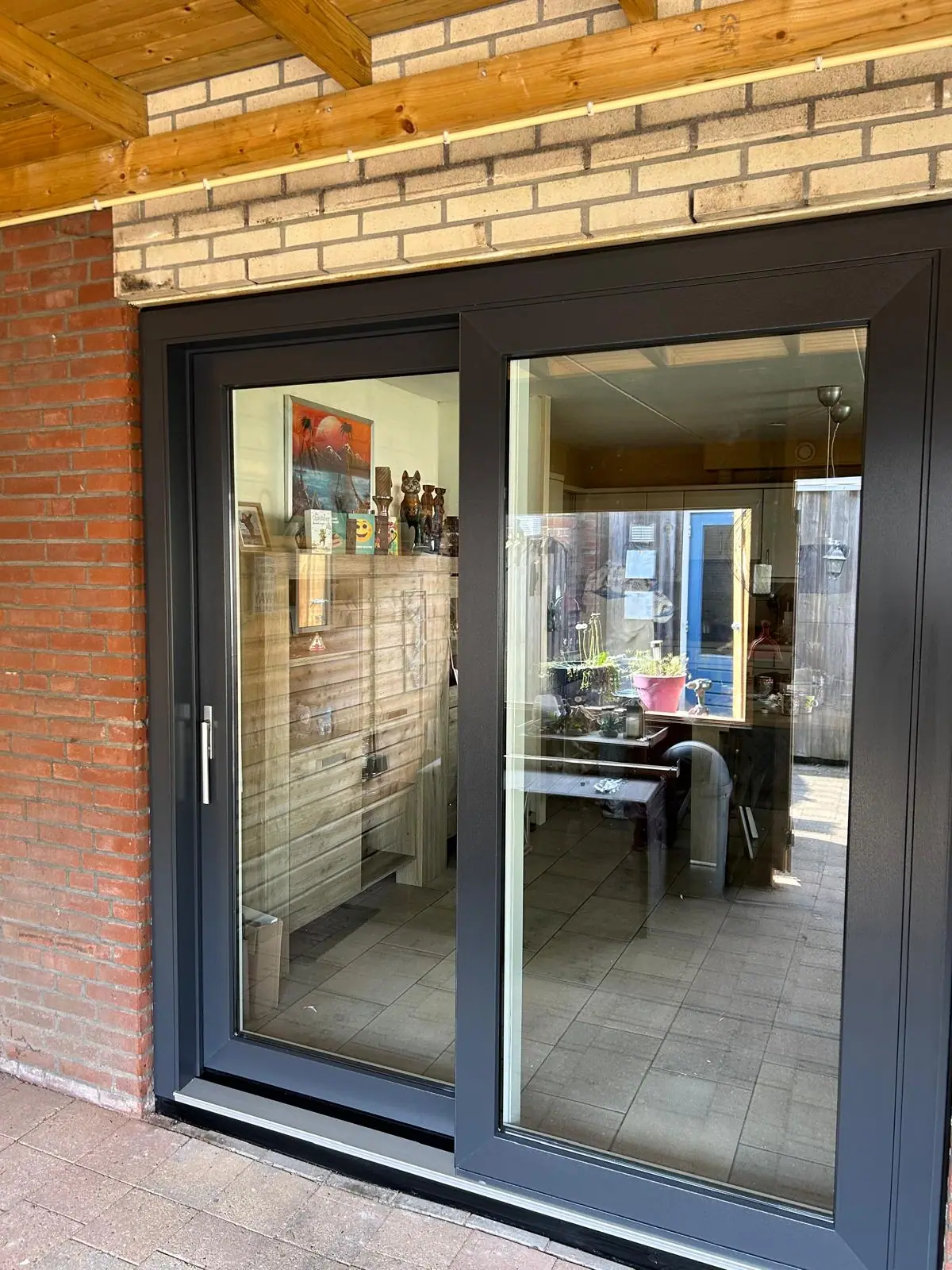 Antracietkleurige kunststof schuifpui geplaatst in een bakstenen woning.